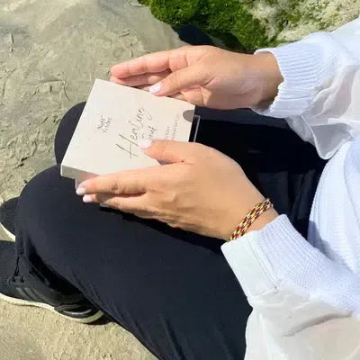 a person outdoors holding a comfort card deck for grief with the word "Healing" written on it